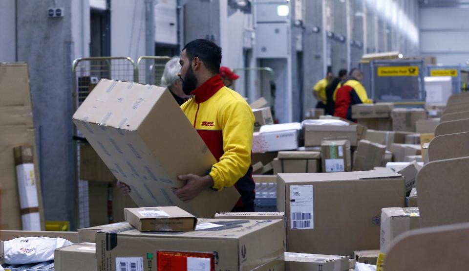 Workers load trucks with parcels at the new distribution centre of the German postal and logistics group Deutsche Post DHL in Berlin November 12, 2013. REUTERS/Tobias Schwarz