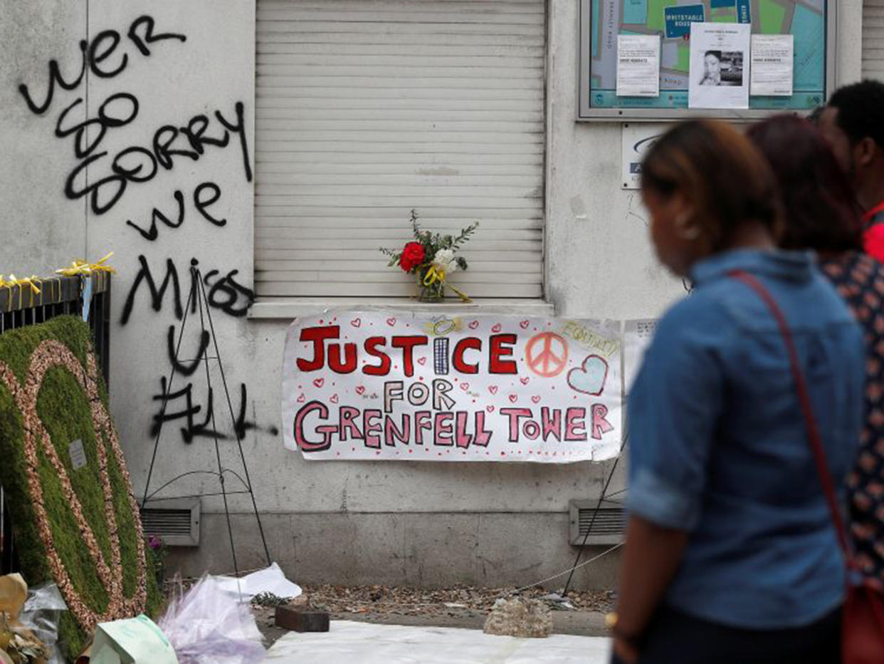 Passers-by look at posters and messages of condolence for the victims of the Grenfell Tower fire, in a street near the tower, in west London: Reuters