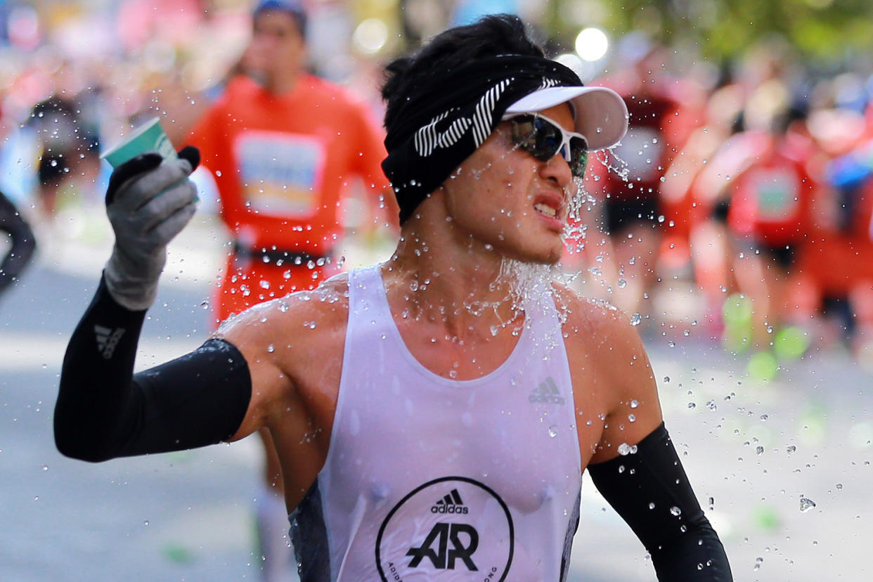 A participant splashes water while running up First Avenue during the 2019 New York City Marathon. (Photo: Gordon Donovan/Yahoo News)