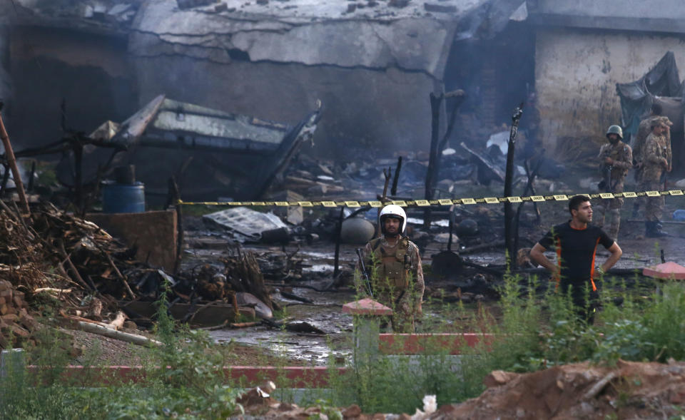 Pakistan army officials examine the site of a plane crash in Rawalpindi, Pakistan, Tuesday, July 30, 2019. A small Pakistani military plane crashed into a residential area near the garrison city of Rawalpindi before dawn, killing some people, officials said. (AP Photo/Anjum Naveed)