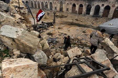 A member of forces loyal to Syria's President Bashar al-Assad attempts to erect the Syrian national flag inside the Umayyad mosque, in the government-controlled area of Aleppo, during a media tour, Syria December 13, 2016. REUTERS/Omar Sanadiki