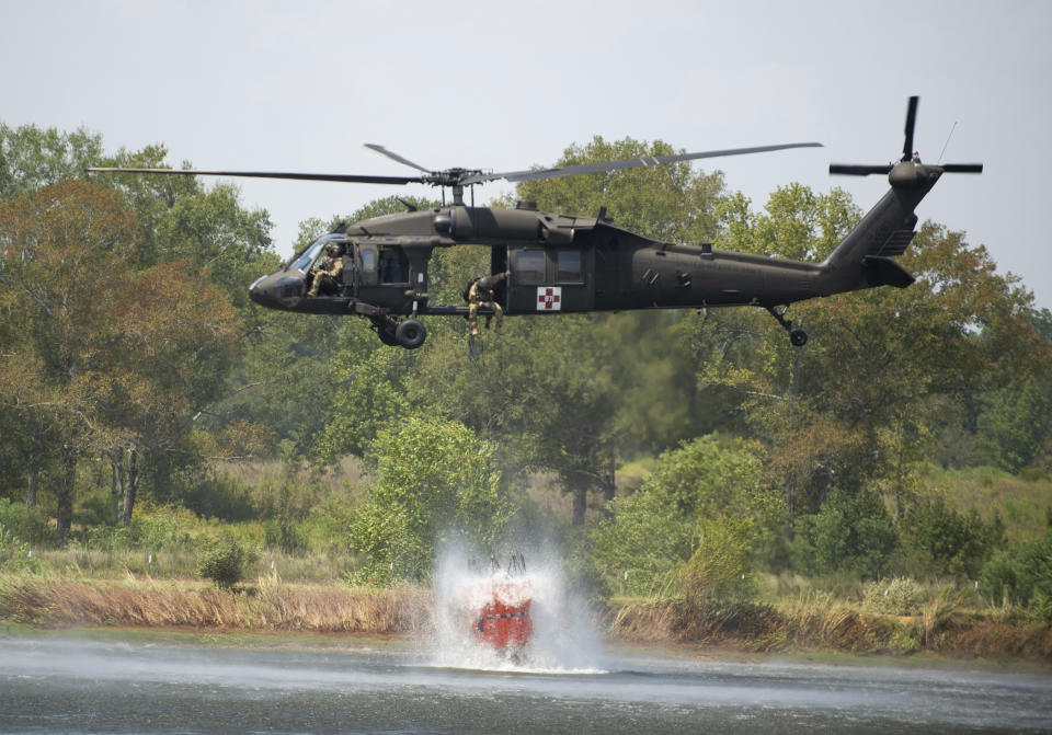 A Blackhawk helicopter fills a 660-gallon basket of water from a farm pond to help battle a wildfire, Thursday, Aug. 24, 2023, in Beauregard Parish, La. The wildfire in southwestern Louisiana forced 1,200 residents in the town of Merryville, located in Beauregard Parish, to evacuate on Thursday. (Brad Bowie/The Times-Picayune/The New Orleans Advocate via AP)