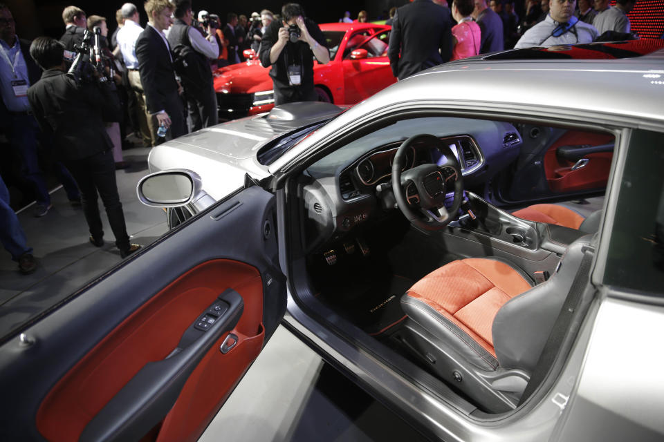 Poeple gather around a 2015 Dodge Challenger after it is introduced at the New York International Auto Show in New York, Thursday, April 17, 2014. (AP Photo/Seth Wenig)