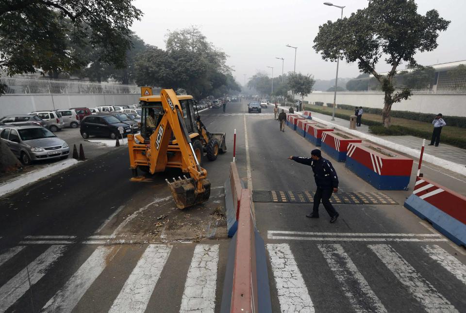 A traffic policeman guides a bulldozer removing the security barriers in front of the U.S. embassy in New Delhi