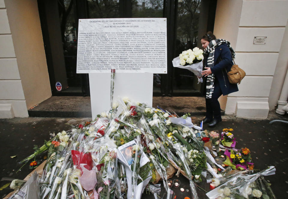 FILE - In this Nov. 13, 2016 file photo, a woman lays flowers next to the memorial plaque for the 90 victims at the Bataclan concert hall in Paris. For more than two weeks, dozens of survivors from the Bataclan concert hall in Paris have testified in a specially designed courtroom about the Islamic State’s attacks on Nov. 13, 2015 – the deadliest in modern France. The testimony marks the first time many survivors are describing – and learning – what exactly happened that night at the Bataclan, filling in the pieces of a puzzle that is taking shape as they speak. (AP Photo/Michel Euler, File)