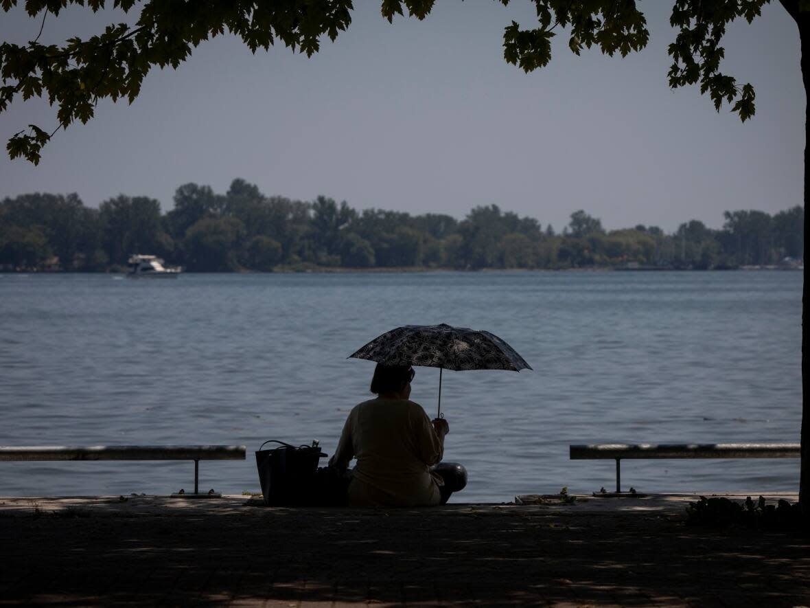 A person stays cool under an umbrella near Lake Ontario in Toronto. (Evan Mitsui/CBC - image credit)