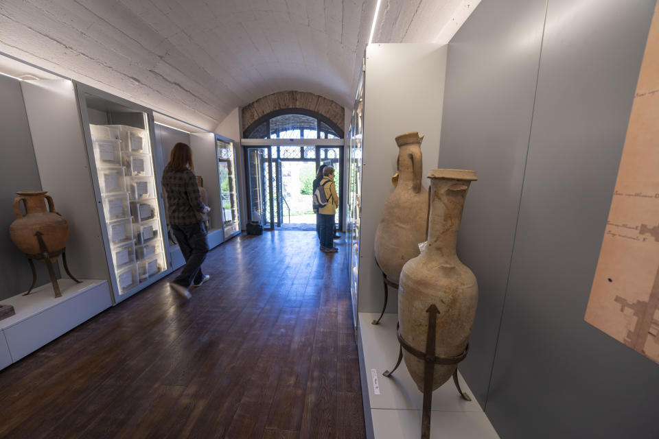 Visitors look at artifacts on display in what had been commercial spaces part of 1st century Emperor Tiberius' palace complex in the Roman Forum in Rome, Wednesday, April 19, 2023. The pieces today on display at the Forum were part of the myriads of findings kept in the Colosseum storehouse that is not open to the public. (AP Photo/Domenico Stinellis)