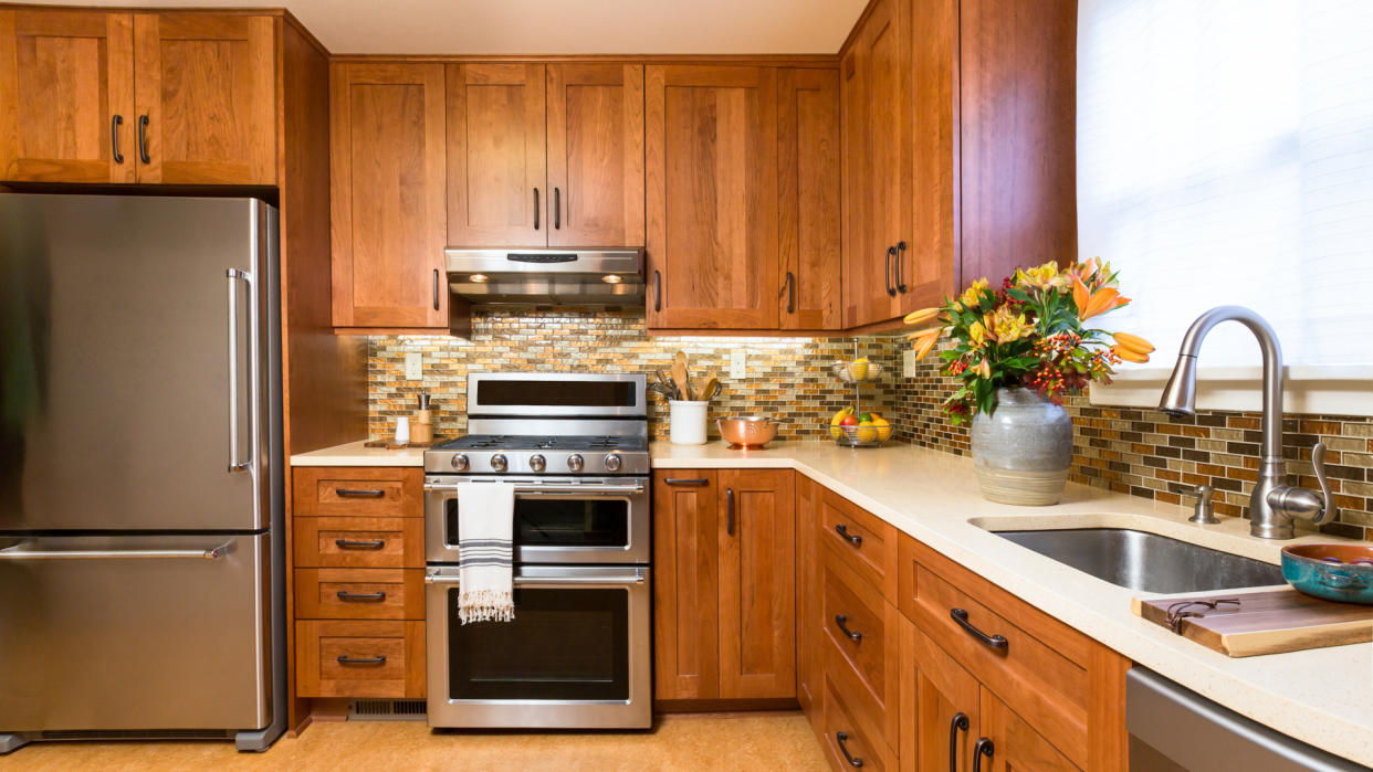 Contemporary upscale home kitchen interior with cherry wood cabinets, quartz countertops, sustainable recycled linoleum floors.