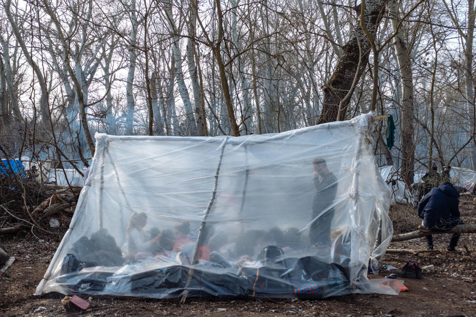 A tent made of propped-up branches, wrapped in plastic. Many migrants slept in the area for days, waiting for a chance to cross the border. | Emin Ozmen—Magnum Photos for TIME