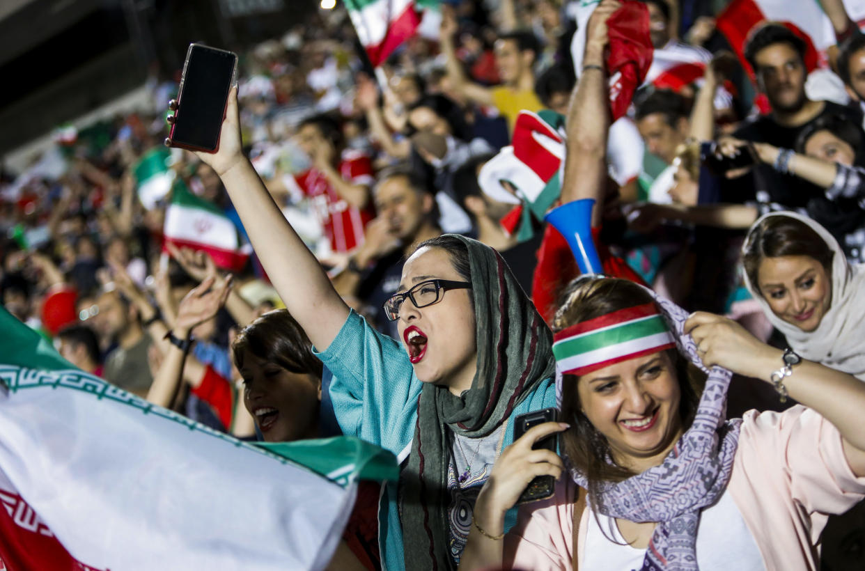 Iranian football supporters wave their national flags as they cheer for their national team during a screening of the Russia 2018 World Cup Group B football match between Iran and Spain in Azadi stadium in the capital Tehran on June 20, 2018. - Tehran's largest football stadium on June 20, 2018 admitted thousands of women together with men for the first time since the Islamic revolution of 1979 as World Cup fever gripped Iran for its evening group game against Spain. (Photo by STRINGER / AFP) / The erroneous mention[s] appearing in the metadata of this photo has been modified in AFP systems in the following manner: [STRINGER] instead of [ATTA KENARE]. Please immediately remove the erroneous mention[s] from all your online services and delete it (them) from your servers. If you have been authorized by AFP to distribute it (them) to third parties, please ensure that the same actions are carried out by them. Failure to promptly comply with these instructions will entail liability on your part for any continued or post notification usage. Therefore we thank you very much for all your attention and prompt action. We are sorry for the inconvenience this notification may cause and remain at your disposal for any further information you may require.        (Photo credit should read STRINGER/AFP/Getty Images)