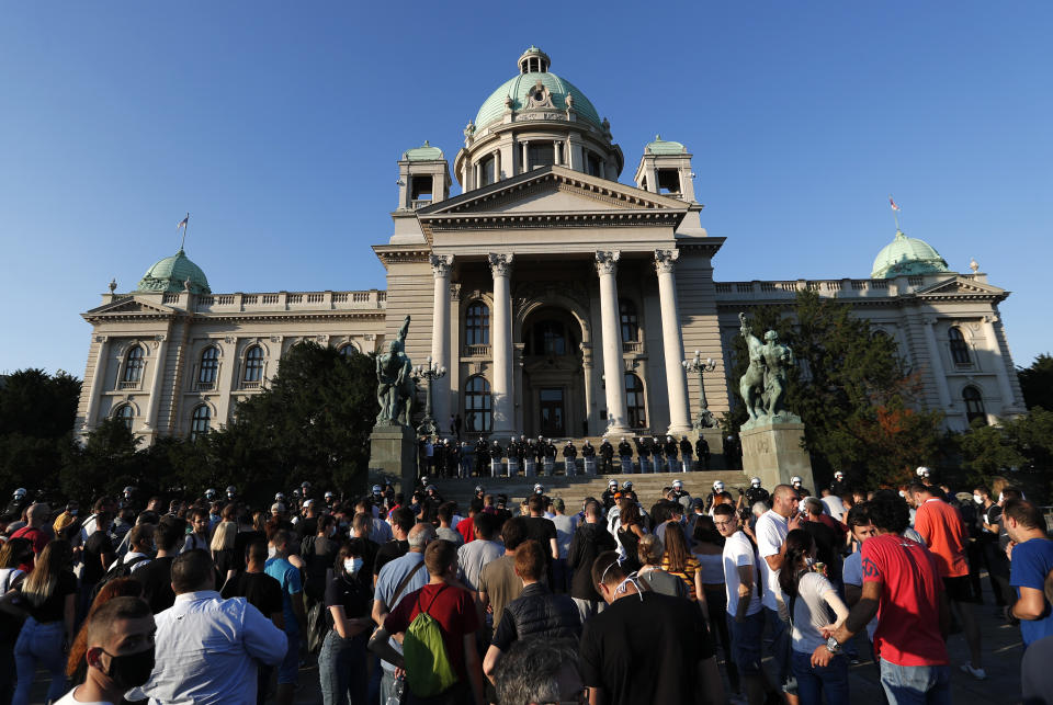 People gather in front of the Serbian Parliament building, heavily guarded by riot police, during a demonstration in Belgrade, Serbia, Wednesday, July 8, 2020. Serbia's president Aleksandar Vucic backtracked Wednesday on his plans to reinstate a coronavirus lockdown in Belgrade after thousands protested the move and violently clashed with the police in the capital. (AP Photo/Darko Vojinovic)