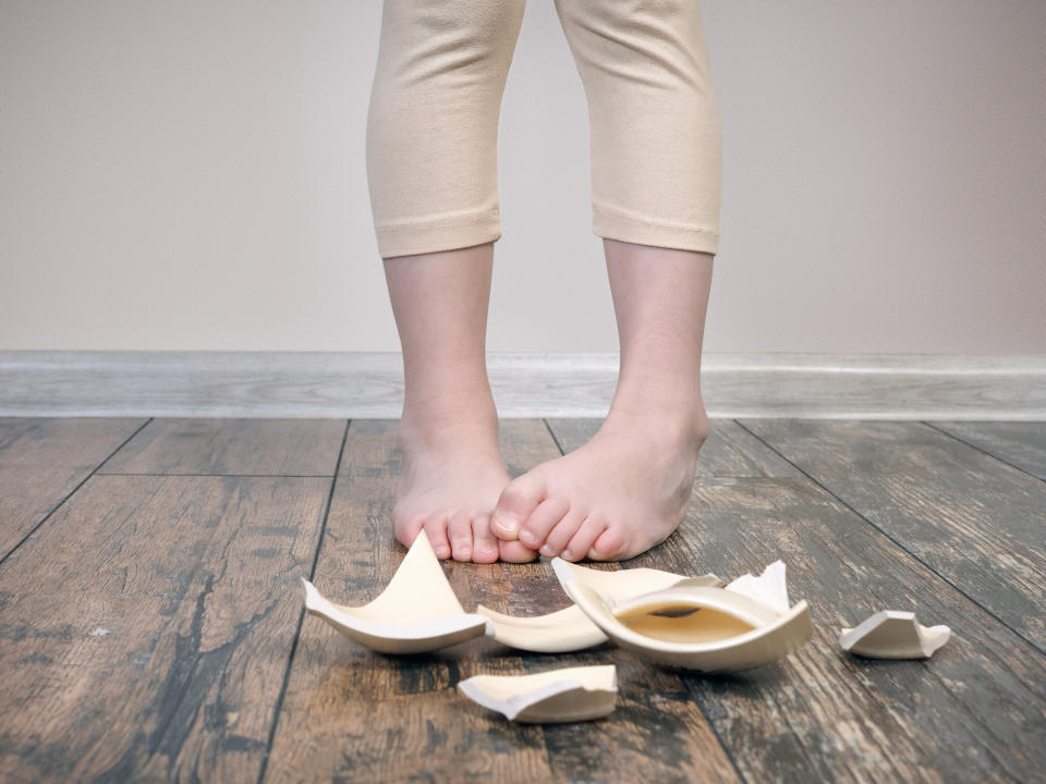 small childs legs and fragments of broken dishes. The concept of fault of the child, the fear of punishment