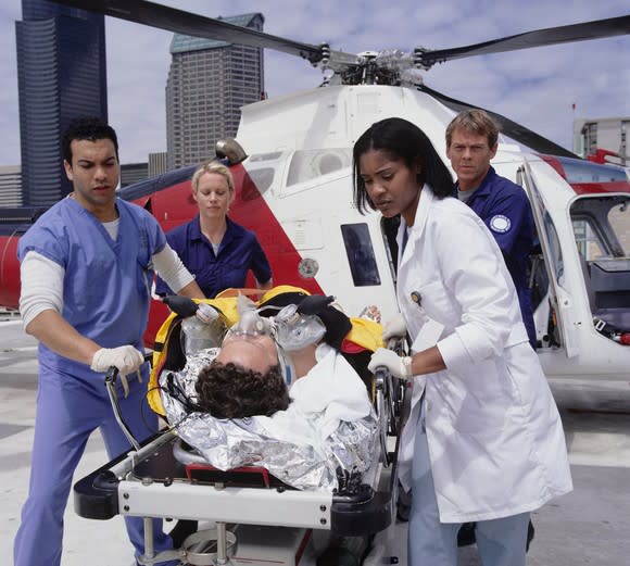 A medical team assists in the transfer of a patient from a medical transport helicopter.