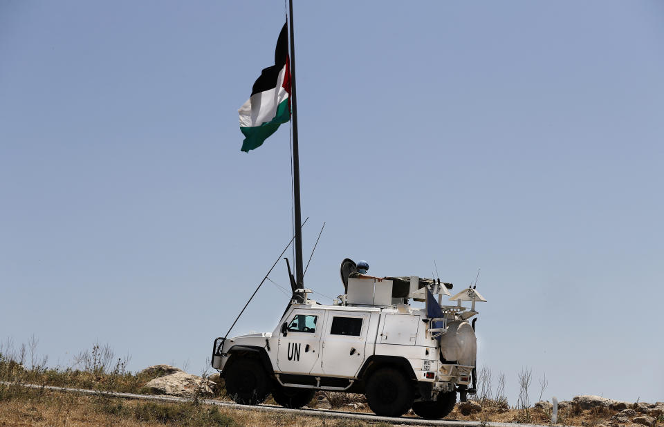 Spanish U.N peacekeepers pass under a Palestinian flag as they patrol on the Lebanese side of the Lebanese-Israeli border in the southern village of Kfar Kila, Lebanon, Saturday, May 15, 2021. On Israel's northern border with Lebanon, Israeli troops opened fire on Friday when a group of Lebanese and Palestinian protesters on the other side cut through the border fence and briefly crossed. (AP Photo/Hussein Malla)