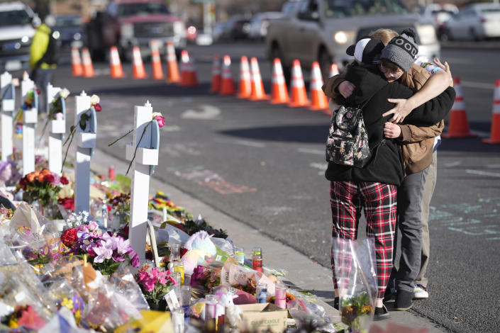 Visitors hug while looking over a makeshift memorial near the scene of a mass shooting at a gay nightclub Wednesday, Nov. 23, 2022, in Colorado Springs, Colo. The alleged shooter facing possible hate crime charges in the fatal shooting of five people at a Colorado Springs gay nightclub is scheduled to make their first court appearance Wednesday from jail after being released from the hospital a day earlier. (AP Photo/David Zalubowski)