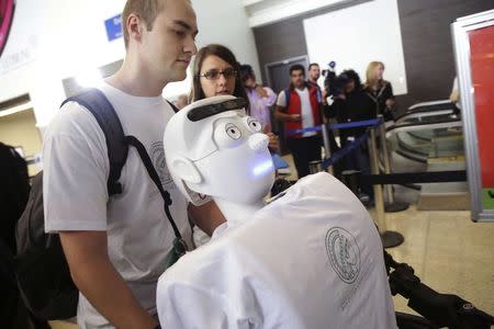 Alexander Herzog, a doctoral student at Max Planck Society, pushes 'Athena', the first 'humanoid' robot to fly as a passenger, as they arrive at Los Angeles International Airport, California December 15, 2014. REUTERS/Jonathan Alcorn