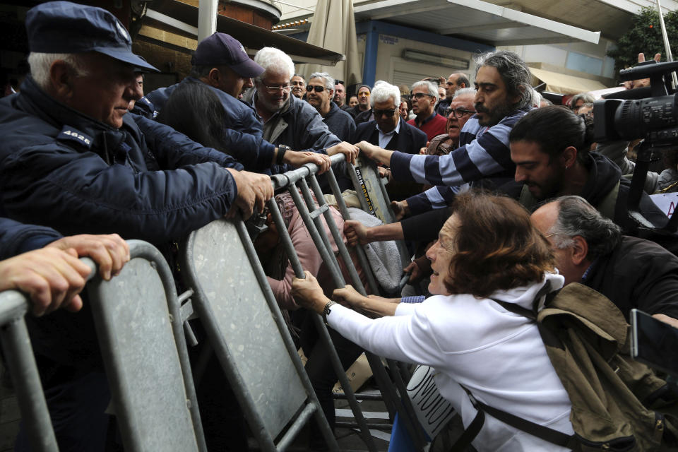 Protesters pull the barriers set up by the police as they demonstrate against the closing of a crossing point straddling a United Nations-controlled buffer zone in divided capital Nicosia, Cyprus, Saturday, Feb. 29, 2020. Around 200 people gathered at the Ledra Street crossing point to voice their opposition to it closing. The Cyprus government said it closed the Ledra Street crossing point along with three others to help with efforts to prevent the possible spread of a new COVID-19 virus either to the breakaway, Turkish Cypriot north or the internationally recognized, Greek Cypriot south. (AP Photo/Petros Karadjias)