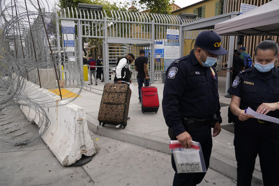 Alex Cortillo, left, of Honduras, walks with his stepbrother as they cross into the United States to begin the asylum process Monday, July 5, 2021, in Tijuana, Mexico. Dozens of people are allowed into the U.S. twice a day at a San Diego border crossing, part of a system that the Biden administration cobbled together to start opening back up the asylum system in the U.S. Immigration advocates have been tasked with choosing which migrants can apply for a limited number of slots to claim humanitarian protection. (AP Photo/Gregory Bull)