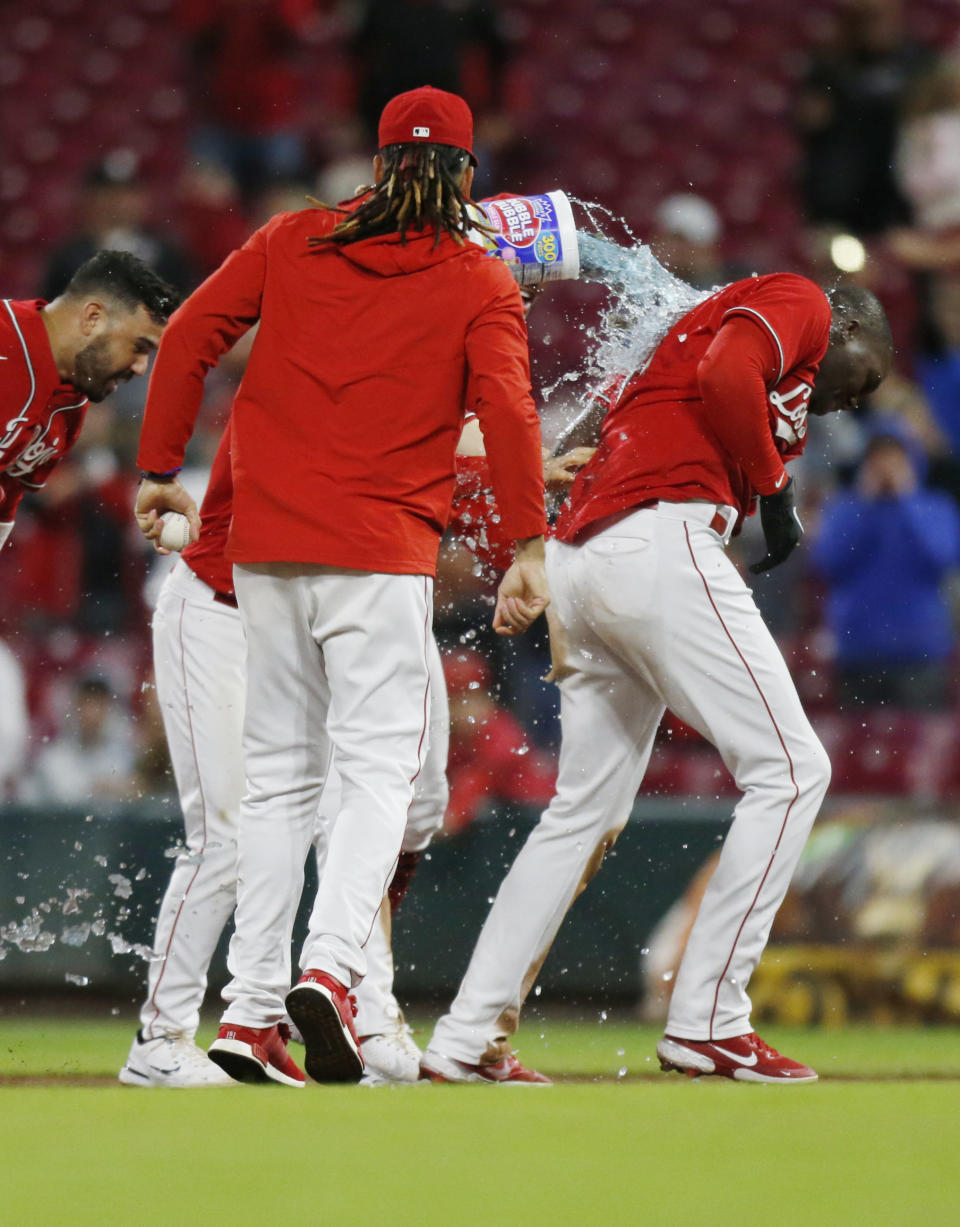 Cincinnati Reds players douse teammate Aristides Aquino, right, after his RBI single in the 11th inning against Washington Nationals pitcher Mason Thompson to win a baseball game in Cincinnati, Ohio, Friday, Sept. 24, 2021. (AP Photo/Paul Vernon)