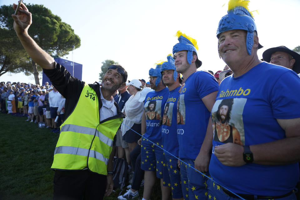 Fans of Europe's Jon Rahm, have their photo taken with a steward on the 12th green during the morning Foursomes matches at the Ryder Cup golf tournament at the Marco Simone Golf Club in Guidonia Montecelio, Italy, Saturday, Sept. 30, 2023. (AP Photo/Alessandra Tarantino)