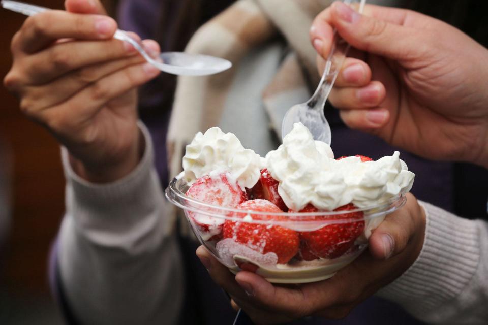 Spectators enjoy a bowl of strawberries and cream on day one of the Wimbledon Lawn Tennis Championships at the All England Lawn Tennis and Croquet Club