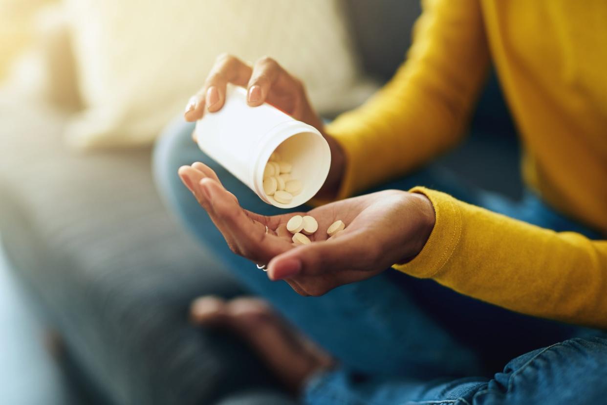 Woman dispensing vitamin supplements into her hand. (Getty Images)