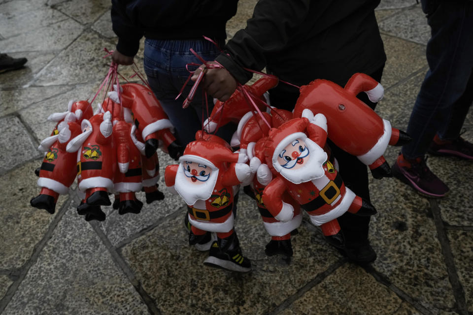 People hold Santa Claus balloons on Christmas Eve, near the Church of the Nativity, traditionally believed to be the birthplace of Jesus, in the West Bank city of Bethlehem, Sunday, Dec. 24, 2023. Bethlehem is having a subdued Christmas after officials in Jesus' traditional birthplace decided to forgo celebrations due to the Israel-Hamas war. (AP Photo/Leo Correa)