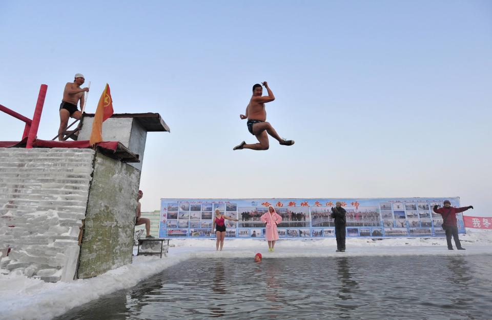 A winter swimmer gestures as he jumps into the icy water of partially frozen Songhua River in Harbin