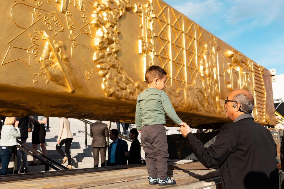 Terence Chen holds 2-year-old Kayce Chen’s hand as he walks next to the Golden Spike Monument after it’s arrival in front of the Utah state Capitol in Salt Lake City on Monday, Oct. 23, 2023. The 43-foot-tall golden spike was commissioned as a public art piece by the Golden Spike Foundation to honor the tens of thousands of railroad workers who built the transcontinental railroad. | Megan Nielsen, Deseret News