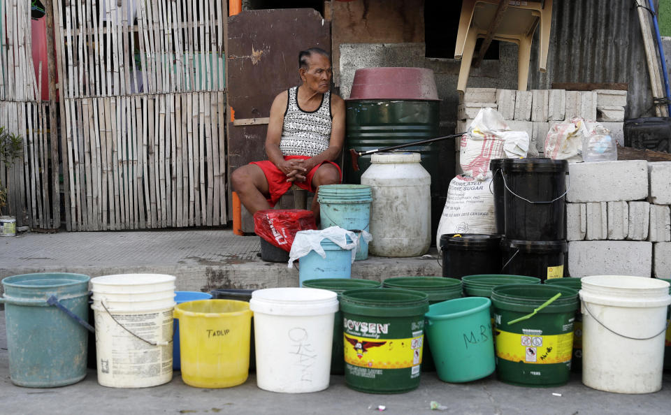 A man sits beside rows of pails as he waits for water trucks return to their area after several days without water in Mandaluyong, metropolitan Manila, Philippines on Thursday, March 14, 2019. Aside from the daily line of residents waiting for water rations from trucks, many businesses like laundry shops, carwash and water purifying stations in some parts of metropolitan Manila have been affected by a water shortage from the Manila Water Company due to low levels at the La Mesa dam and the onset of El Nino which causes below normal rainfall conditions. (AP Photo/Aaron Favila)