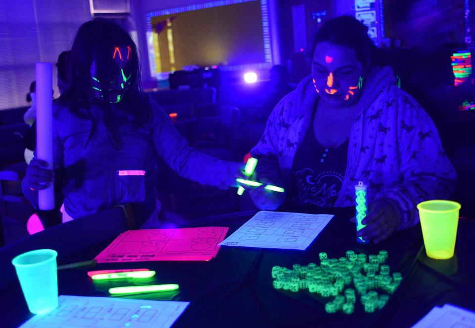 Josie Green, 8, plays a math game called "Shake and Roll" with her mom, Jen Green, on Friday March 1, 2024, during the 2nd annual Family Glow Night at B.L. Miller Elementary School.