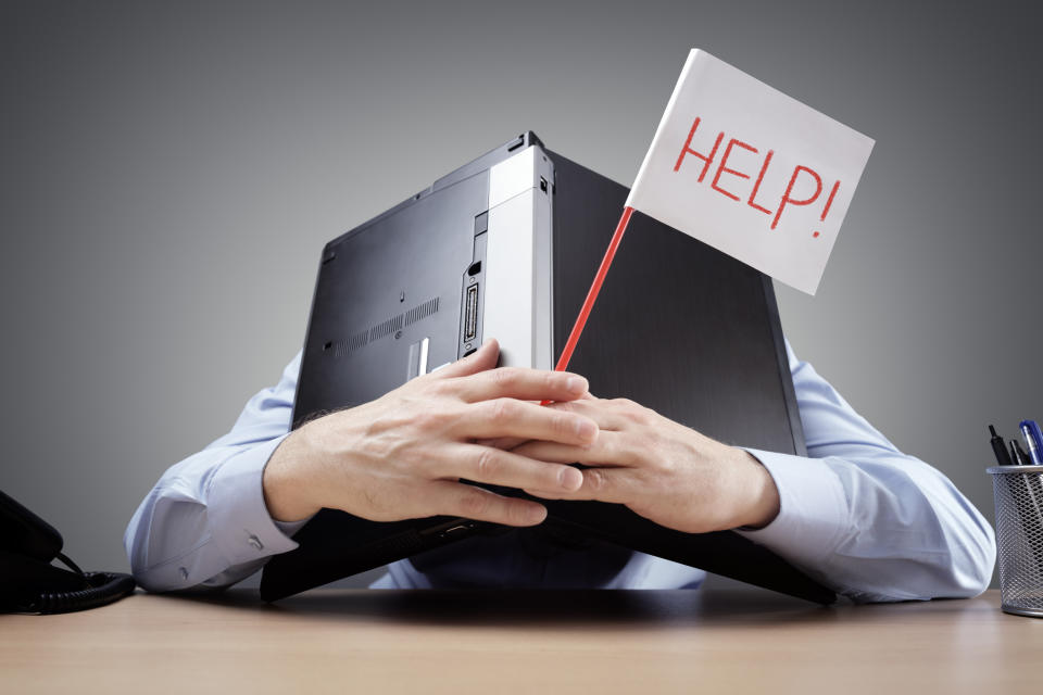 A man with a laptop folded over his head, holding a sign that reads "help!"