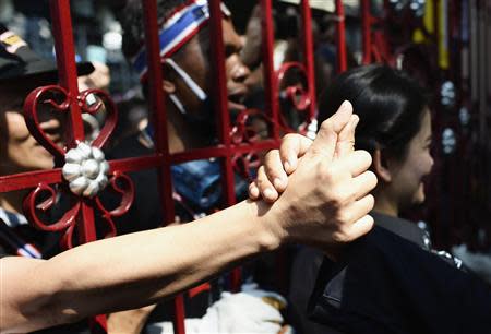 An anti-government protester touches the hand of a police officer through the main gate of the Thai Police Headquarters in Bangkok December 4, 2013. REUTERS/Dylan Martinez