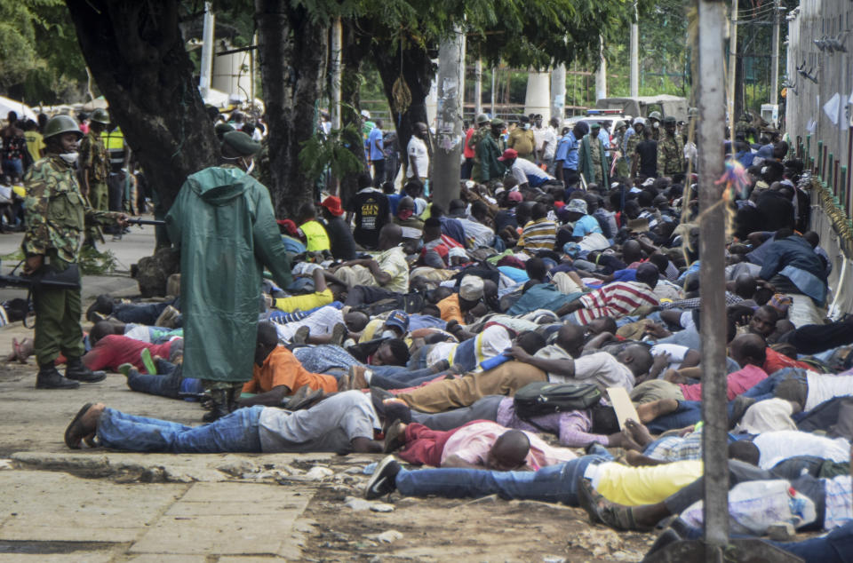 Police force ferry passengers to lie face down on the ground after firing tear gas and detaining them, after new measures aimed at halting the spread of the new coronavirus instead caused a crowd to form outside the ferry in Mombasa, Kenya Friday, March 27, 2020. The new measures required public transport vehicles to drop passengers 1km away and walk to the ferry terminal and then queue, but passengers fearing they would get stuck before a 7pm curfew started crowding to get on causing police to fire tear gas and round up the passengers. (AP Photo)