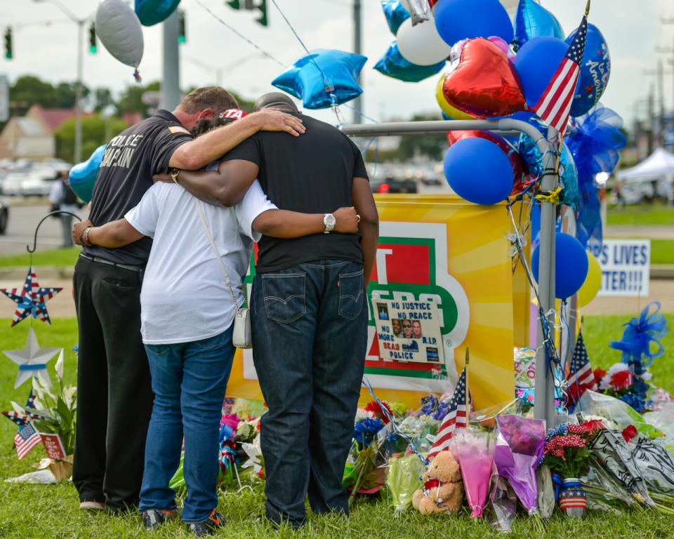 People gather around a memorial at the location where Baton Rouge police officers were killed and wounded, Monday, July 18, 2016, in Baton Rouge, La. (Scott Clause/The Daily Advertiser via AP)