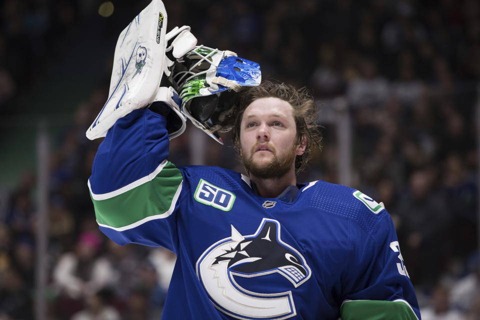 FILE - In this Jan. 27, 2020 file photo, Vancouver Canucks goalie Thatcher Demko takes off his mask during a stoppage in play against the St. Louis Blues during the first period of an NHL hockey game in Vancouver, British Columbia. NHL players are debating the merits of quarantining away from family members as part of a potential resumption of the season. Young and single, Demko said quarantining to play hockey wouldn’t be a problem for him. “I don’t have too many roots,” the 24-year-old said. “I’ve been living pretty much out of my car for the most part for the last six, seven years just going from place to place.” (Darryl Dyck/The Canadian Press via AP, File)