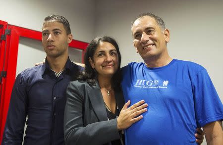 Felix Baez (R), a member of the International Contingent Brigade "Henry Reeve", who was infected with Ebola in Sierra Leone, poses for a photo with his wife Vania Ferrer and his son Alejandro Baez during a news conference in Havana December 6, 2014. REUTERS/Yamil Lage/Pool