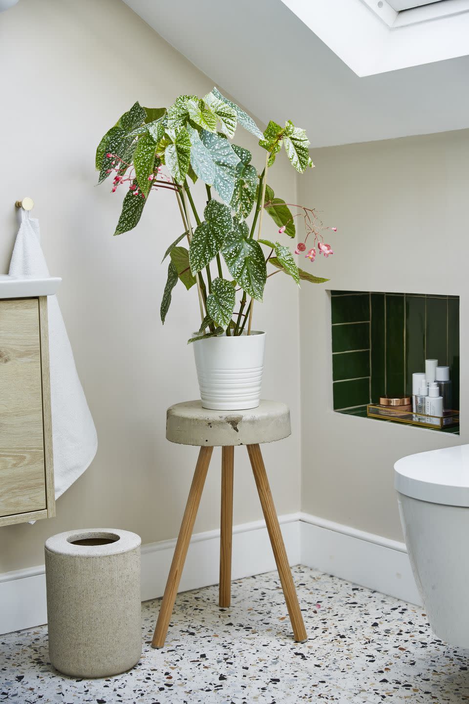 a small bathroom with sloping ceiling and a green tiled nook shelf