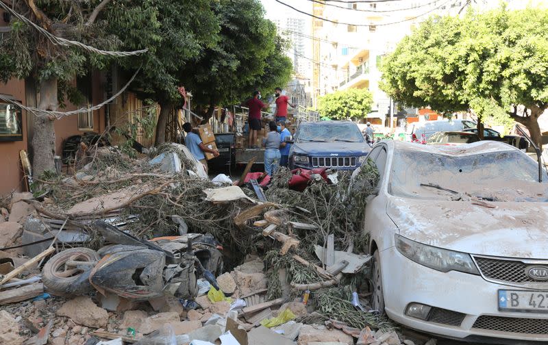 People are seen near rubble and damaged vehicles following Tuesday's blast in Beirut's port area