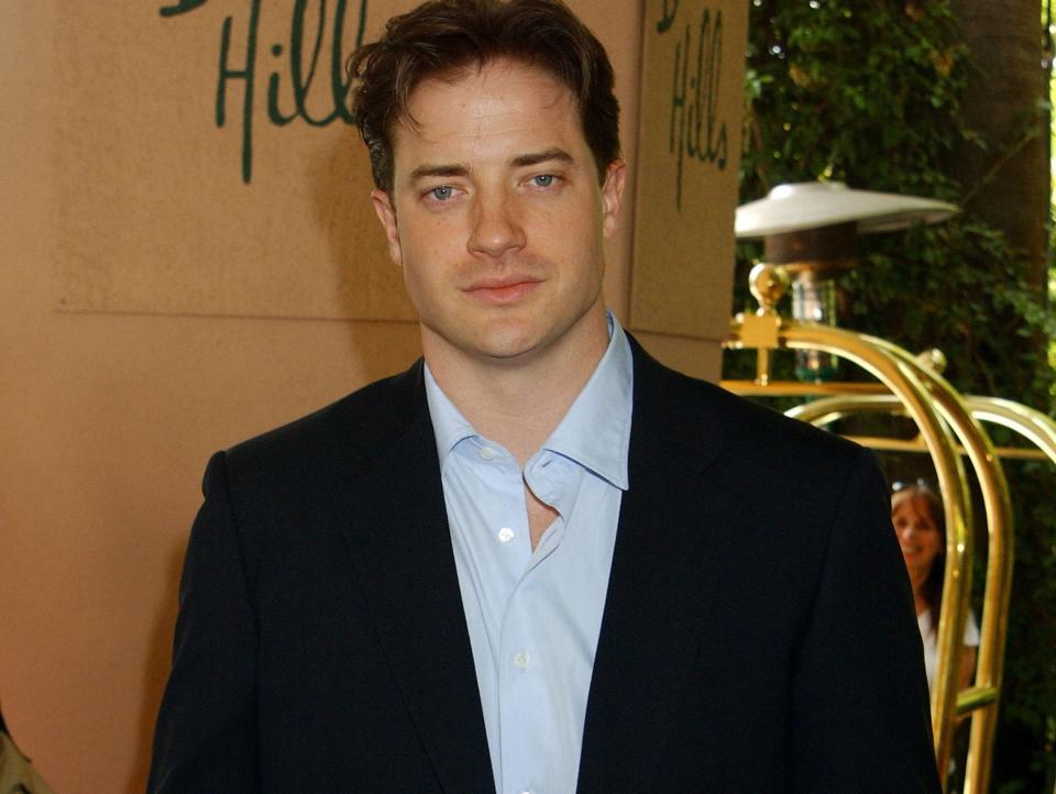 Brendan Fraser, in a black suit and blue shirt, poses for photos at a Hollywood Foreign Press Association luncheon in Los Angeles in July 2003.
