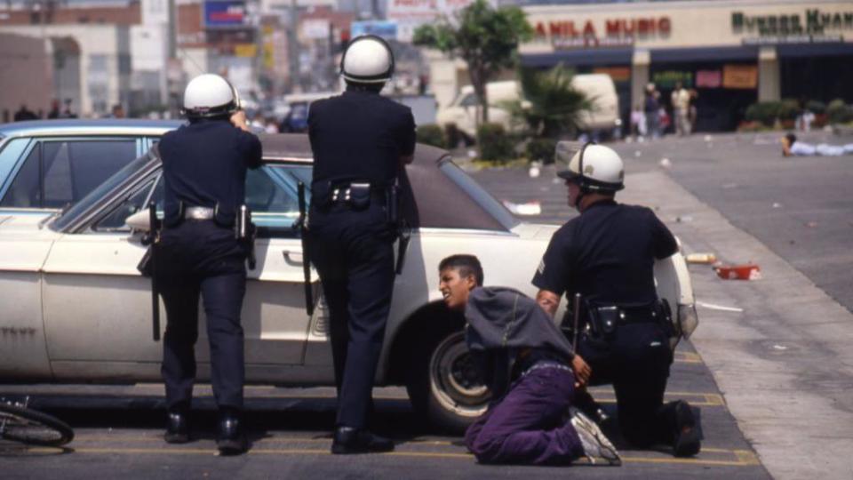 Policías tratan de protegerse contra los manifestantes durante los Disturbios de Los Ángeles de 1992