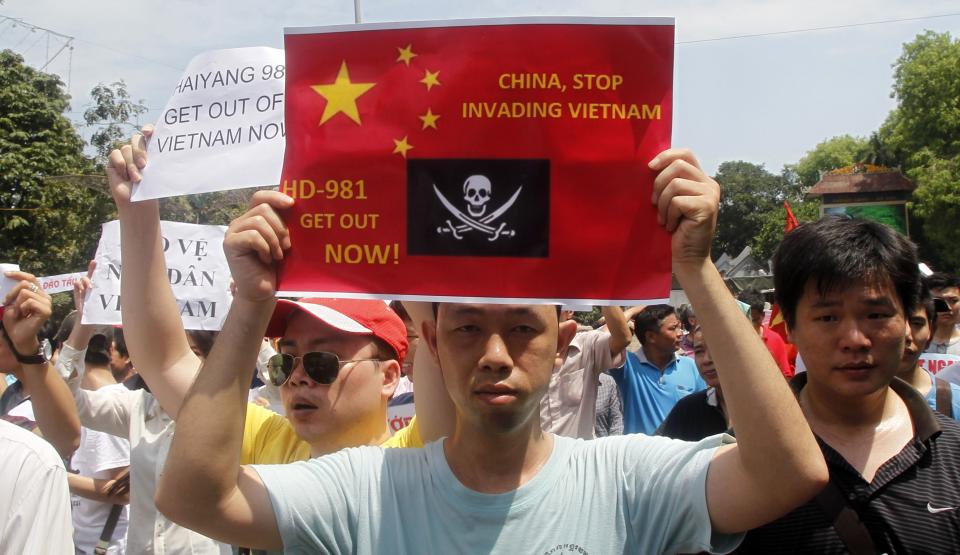 Protesters hold anti-China placards while marching in an anti-China protest on a street in Hanoi May 11, 2014. Hundreds rallied on Sunday in Vietnam's biggest cities to denounce China's setting up of a giant oil rig in the South China Sea, a rare protest likely to prolong a tense standoff between the two communist neighbours. REUTERS/Kham (VIETNAM - Tags: POLITICS CIVIL UNREST)