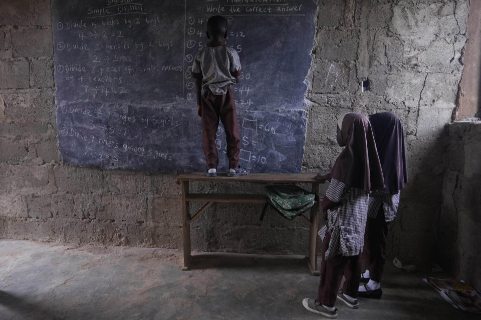 Students work out math problems on a blackboard inside a classroom lit by sunlight that streams in through the windows and doors, at the Excellent Moral School that has no access to electricity in Ibadan, Nigeria, May 28, 2024. (AP Photo/Sunday Alamba)