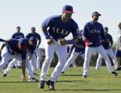 Seattle Seahawks quarterback Russell Wilson, center, runs through morning stretches with the Texas Rangers during spring training baseball practice, Monday, March 3, 2014, in Surprise, Ariz. (AP Photo/Tony Gutierrez)