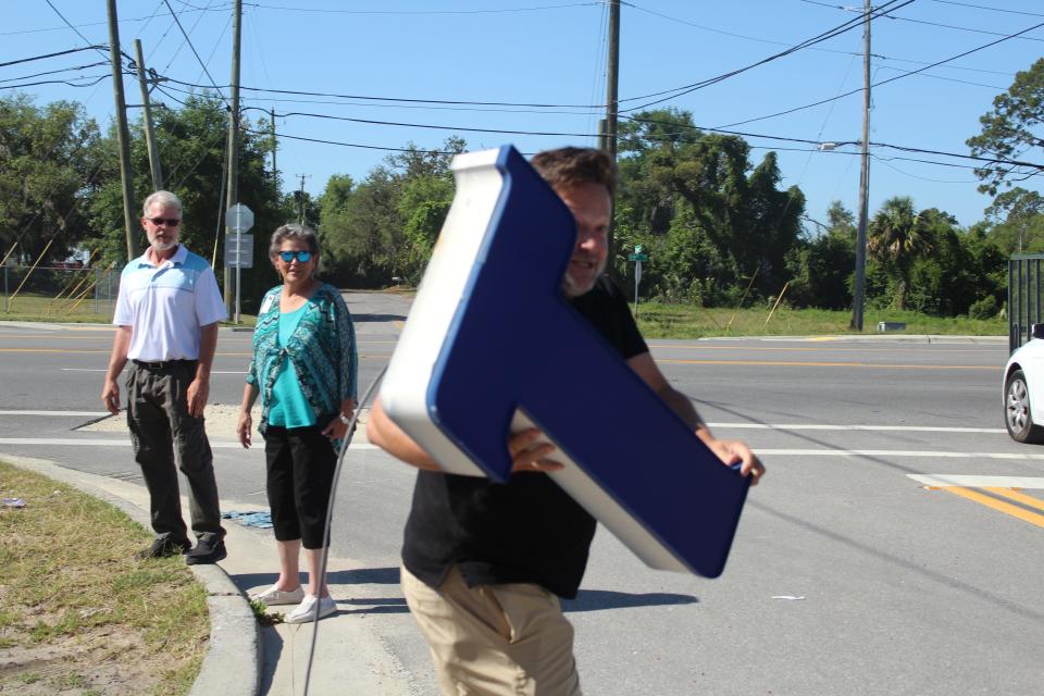 Spectators watch as a man hops out of his truck to grab the fallen "T" from the demolished Toy Box building on Wednesday.