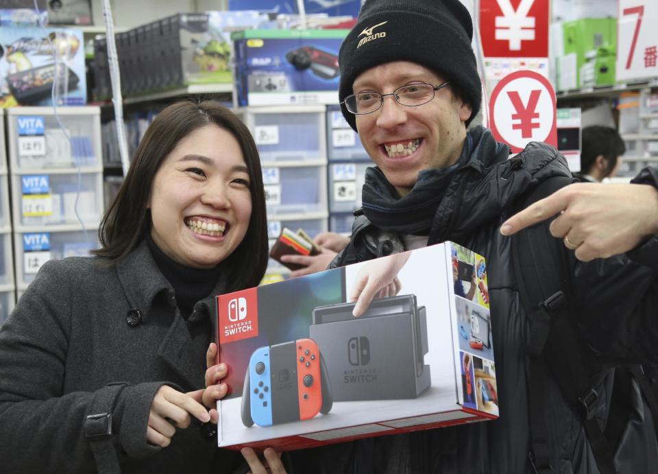 David Flores, 34 years old, right, and his wife Nao Imoto, 31 years old, show off Nintendo's newest computer game consoles "Switch" at a retail store Bic Camera in central Tokyo. Friday, March 3, 2017. (AP Photo/Koji Sasahara)