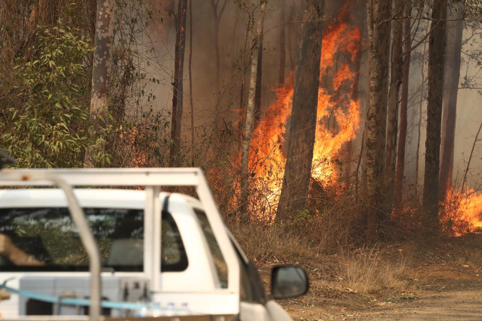 Local residents are seen near a bushfire burning next to Busby's Flat Road in Busbys Flat, northern NSW, Wednesday, October 9, 2019. (AAP Image/Jason O'Brien) NO ARCHIVING