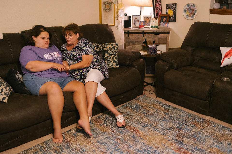 Wanda Felty sits with her daughter Kayla in their home in Norman, Okla., on July 19, 2022. Kayla's brain did not fully form in utero; she is mostly non-verbal and has significant visual impairment, among other medical issues. Felty and her husband are Kayla's primary caretakers.<span class="copyright">Morgan Lieberman</span>