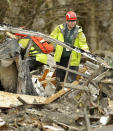 A search and rescue worker clears debris from a house Tuesday, March 25, 2014, on the western edge of the massive mudslide that struck near Arlington, Wash., on Saturday, killing at least 14 people and leaving dozens missing. (AP Photo/Ted S. Warren, Pool)