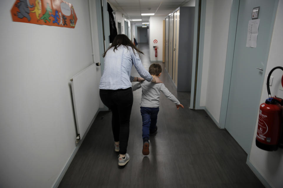 Maelle Allanore, a psychomotor therapist runs down a corridor with a boy in the pediatric unit of the Robert Debre hospital, in Paris, France, Tuesday, March 2, 2021. (AP Photo/Christophe Ena)